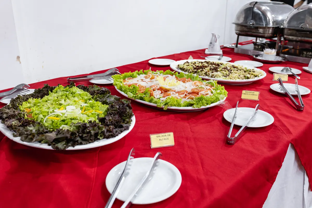 Mesa de buffet com saladas variadas sobre toalha vermelha no restaurante do hotel.