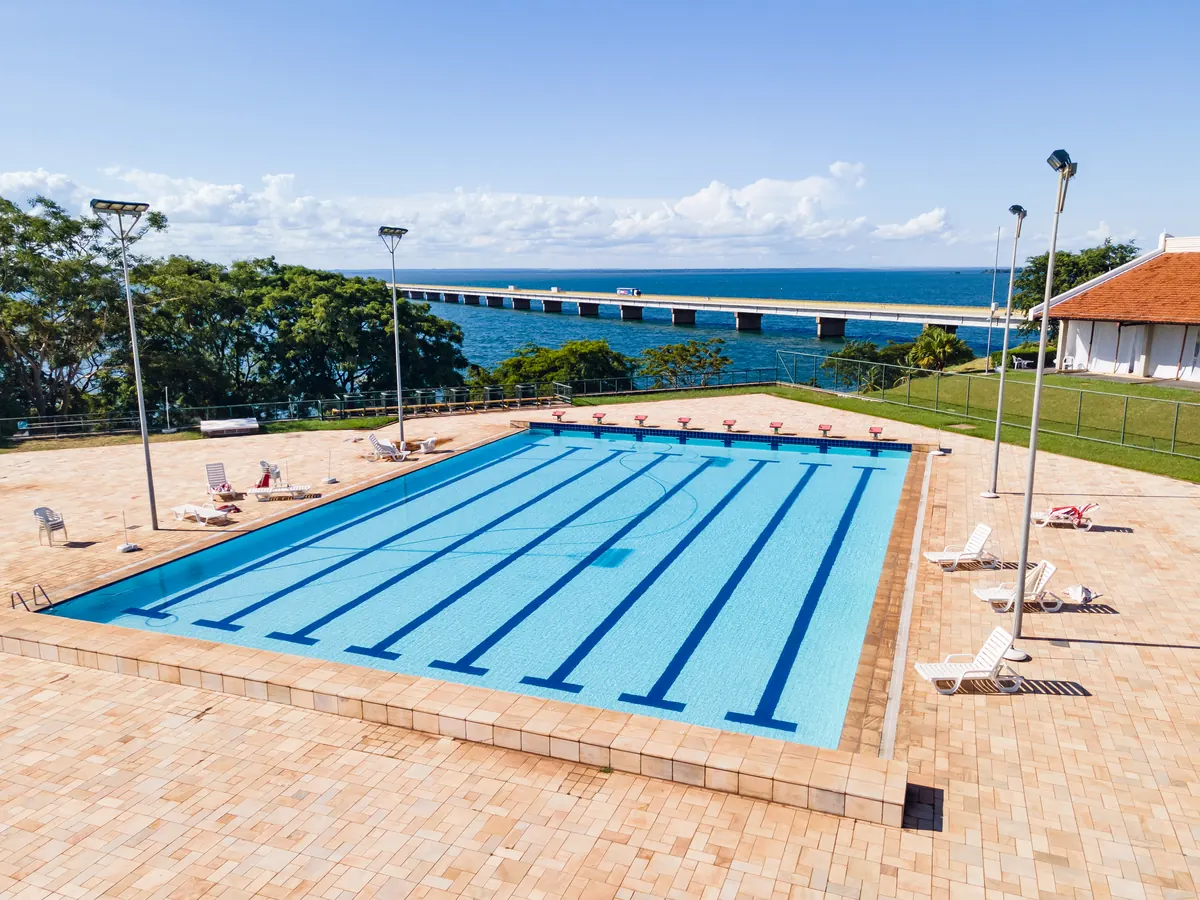 Piscina semiolímpica com raias, holofotes e a ponte sobre o rio ao fundo