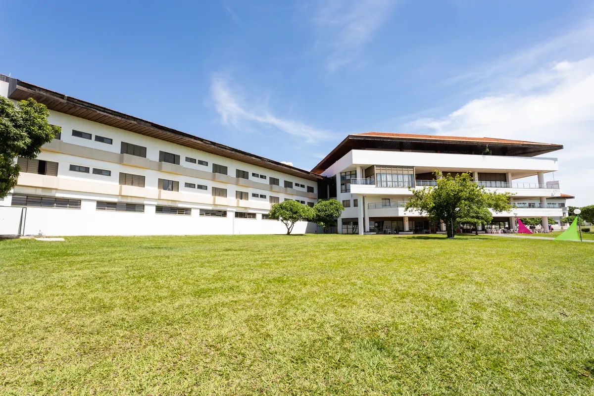 Vista ampla dos blocos do hotel com extenso gramado e céu azul