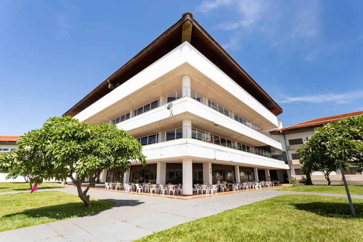 Prédio principal do hotel visto da quina, com terraço de mesas no térreo