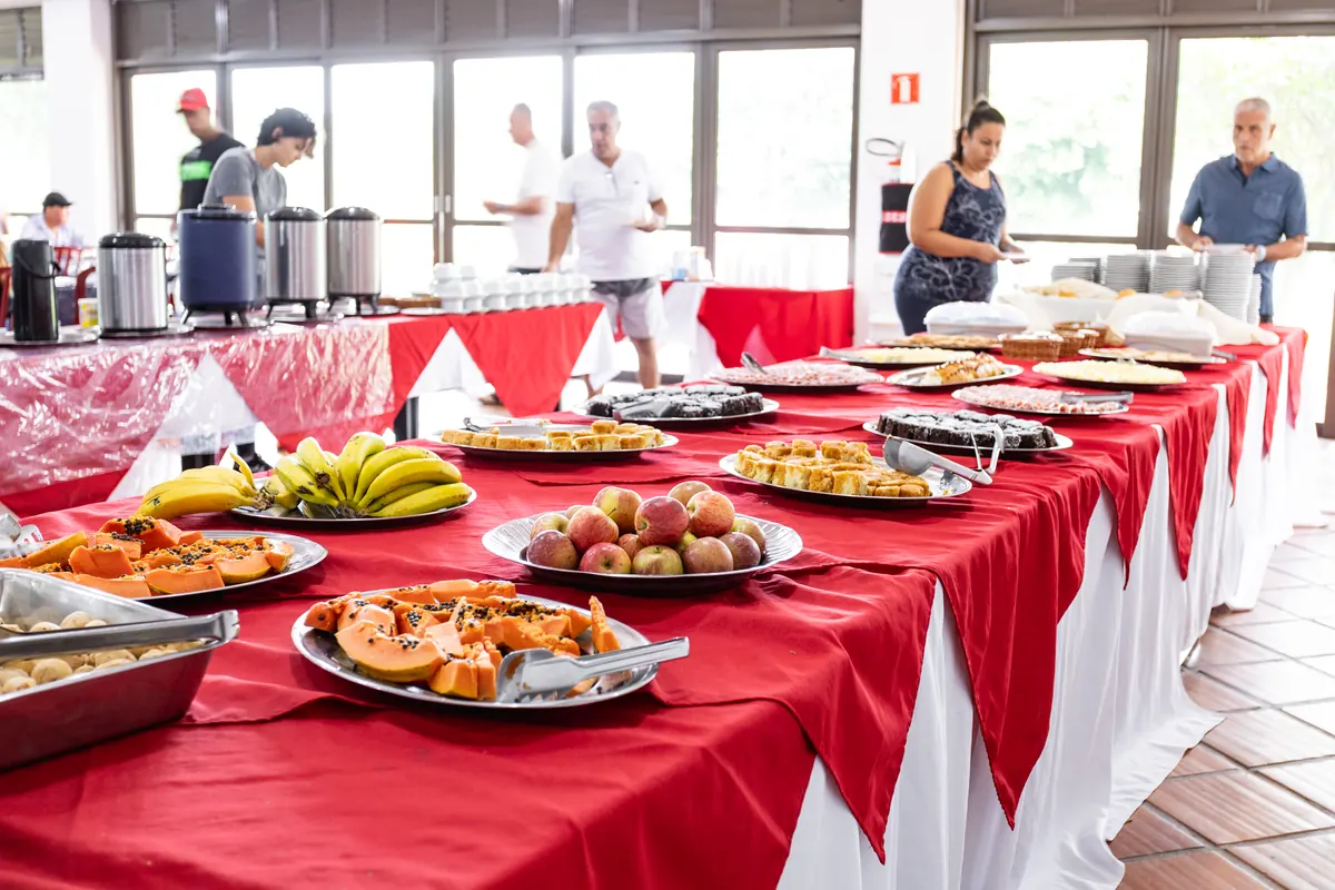Buffet de café da manhã em mesa longa com frutas tropicais e janelas amplas do restaurante