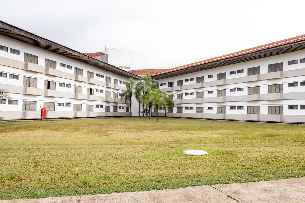 Prédio de hospedagem com palmeiras no pátio central e extenso gramado